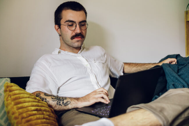 Man with a mustache working on laptop at home
