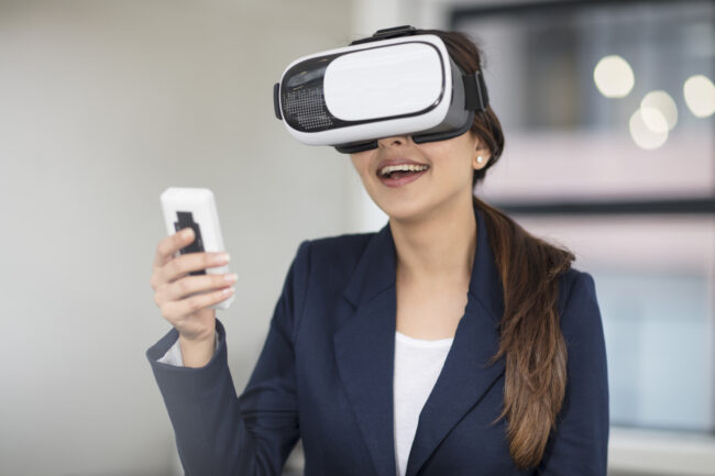 Smiling businesswoman wearing VR glasses in office