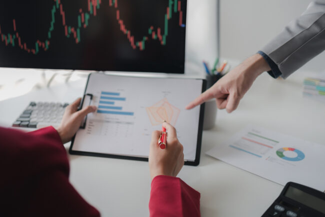 Two investors look at stock insights to analyze risk, stock investing businessman analyzing stock market rise and fall chart, stock market investor, profit making. investment concept.